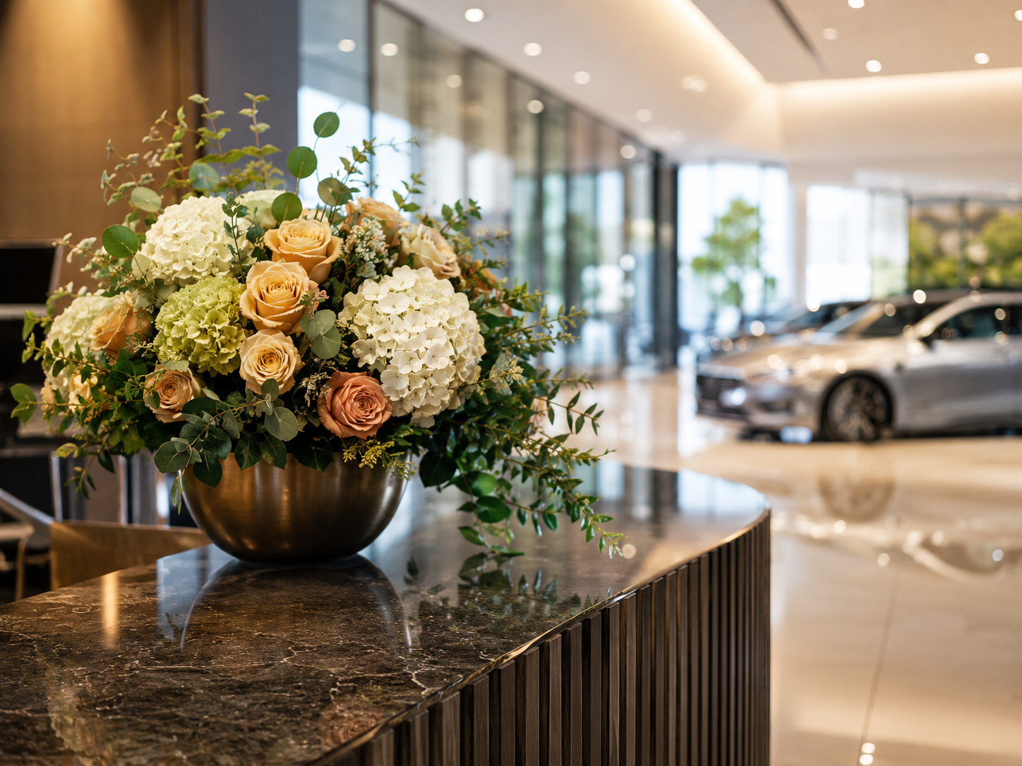 Reference visual: a statement floral arrangement on a car dealership reception counter with showroom vehicles in the background